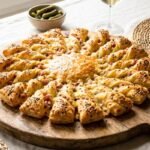 Questo sole di pasta sfoglia a 24 raggi da staccare con le dita ha trasformato ogni mio aperitivo e il segreto sono le torsioni tutte nello stesso verso a 180°C per 40 minuti